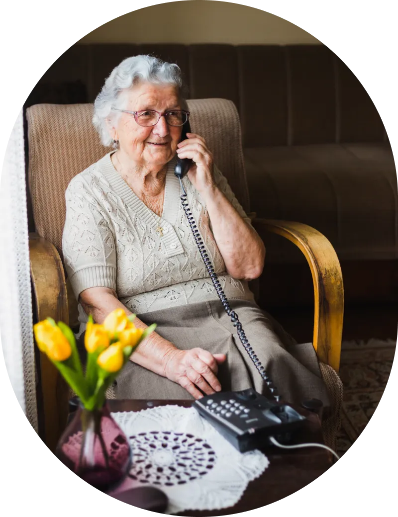 An elderly woman talking on her home phone